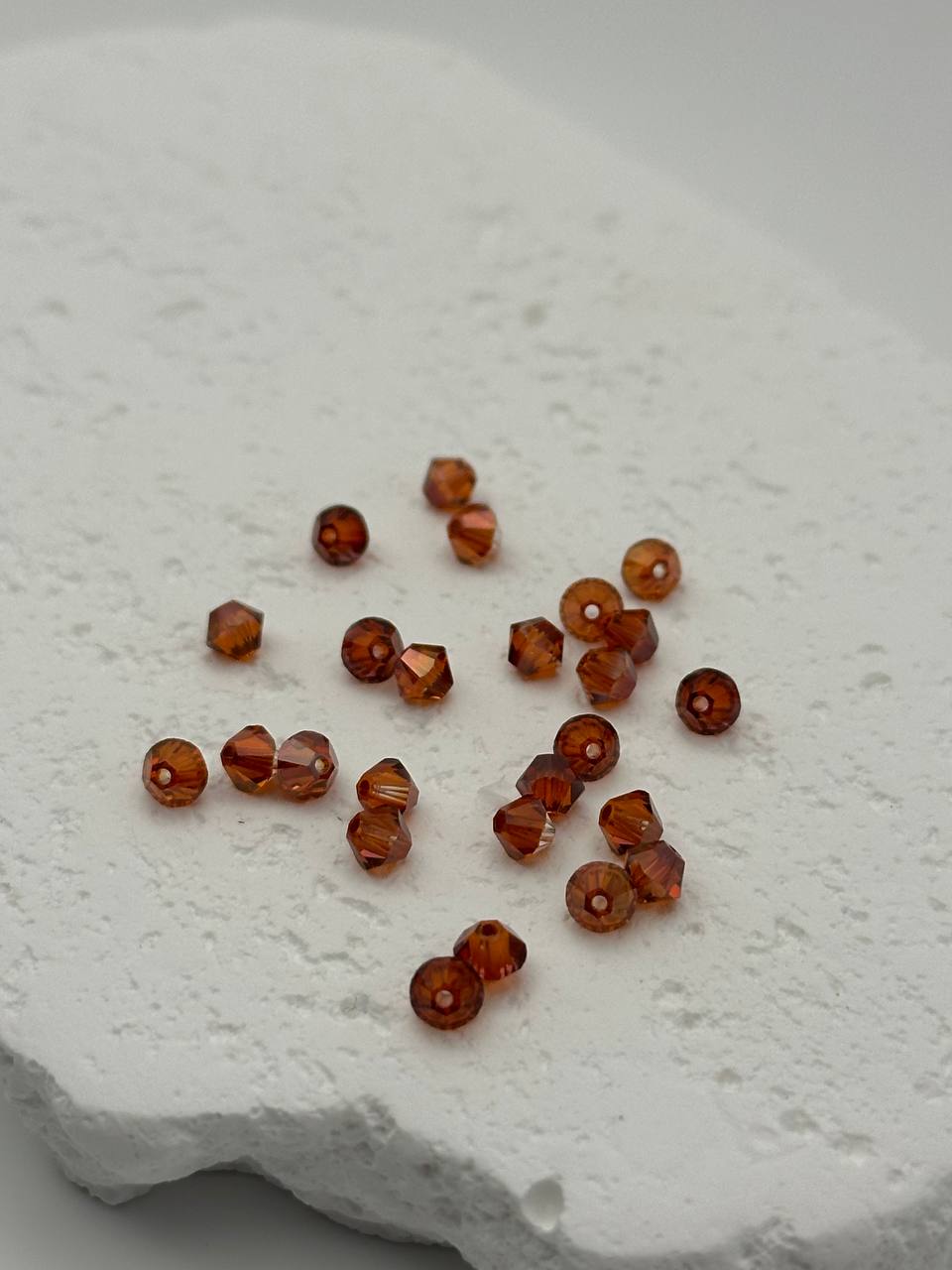 Brown bicone beads scattered on a textured white surface
