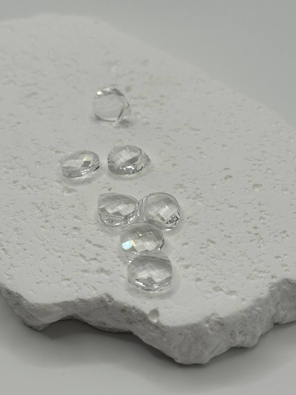 Clear crystal briolettes on a textured white surface