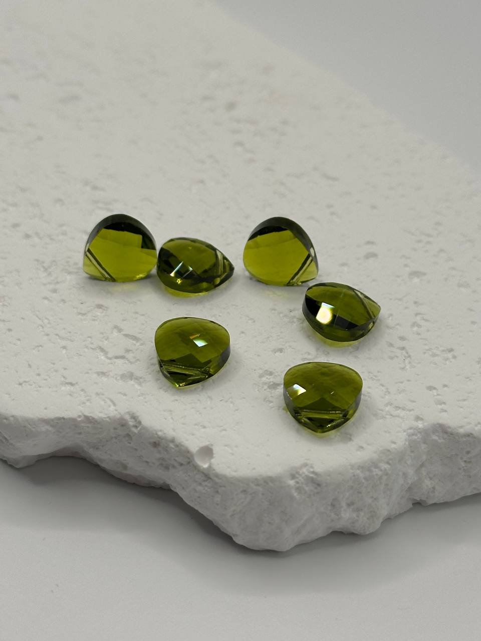 Green crystal briolettes on a textured white surface