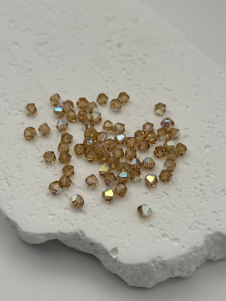 Brown AB bicone beads on a textured white surface