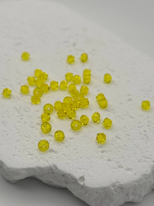 Citrine bicone beads scattered on a textured white surface