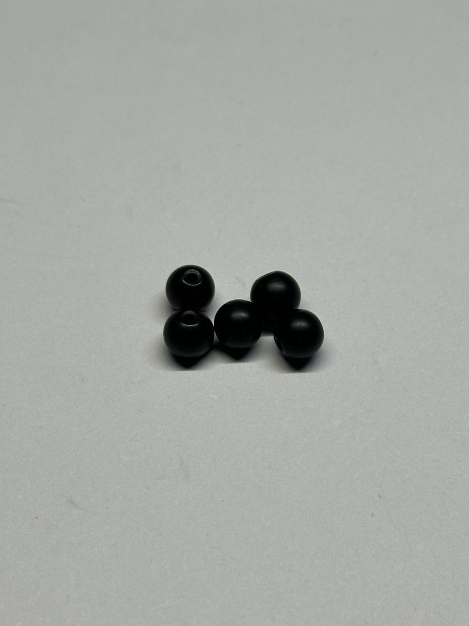 Five black beads on a light gray background