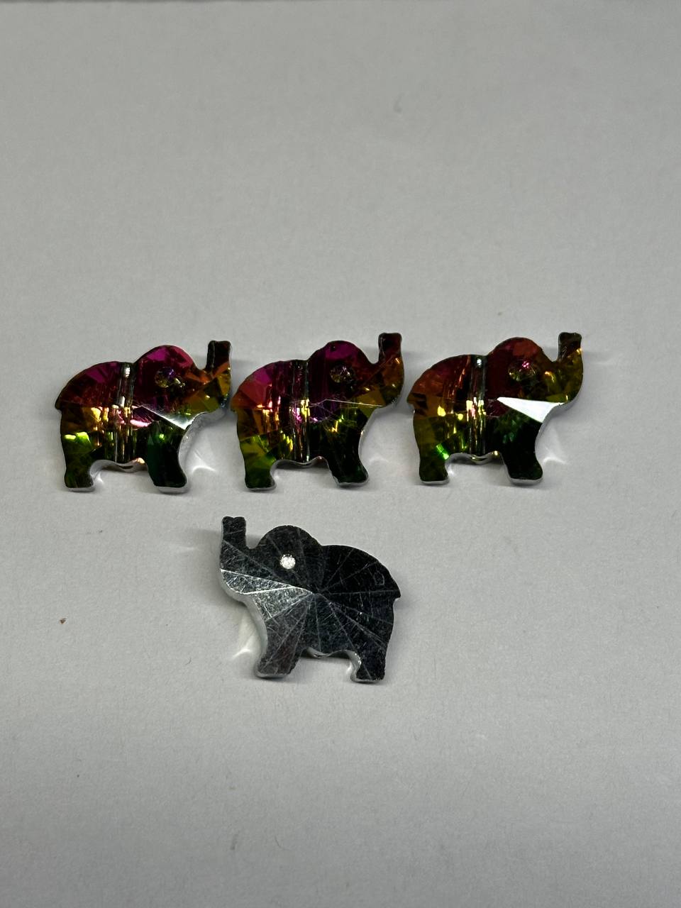 Set of colorful elephant-shaped beads on a gray background