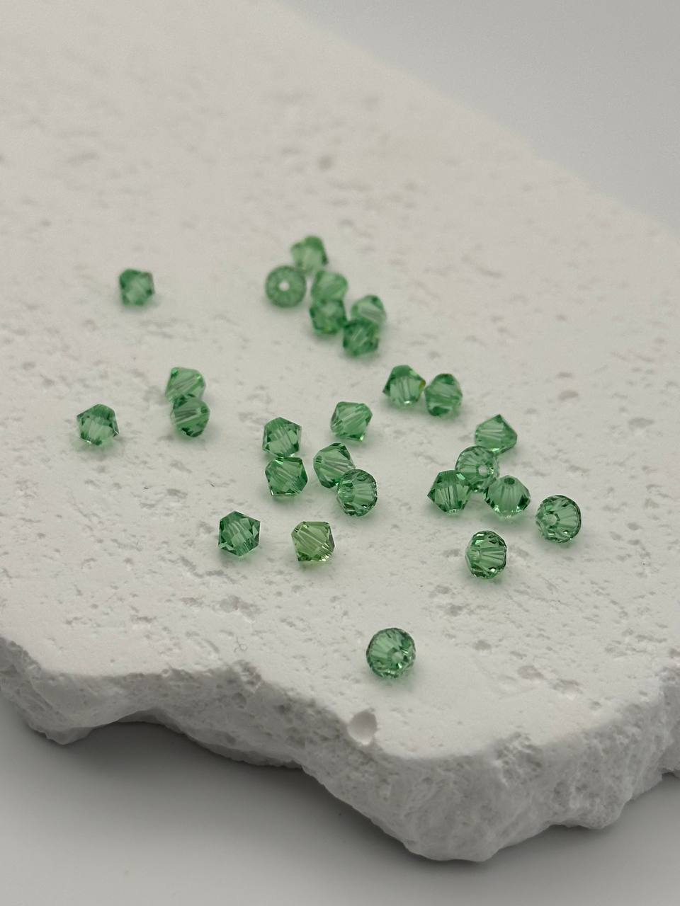 Green bicone beads on a textured white surface