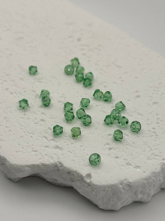 Green bicone beads on a textured white surface