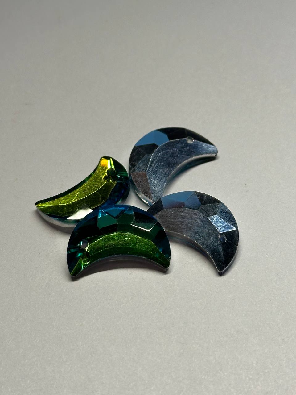 Four foil back reflective glass pieces in green, blue on a light gray background