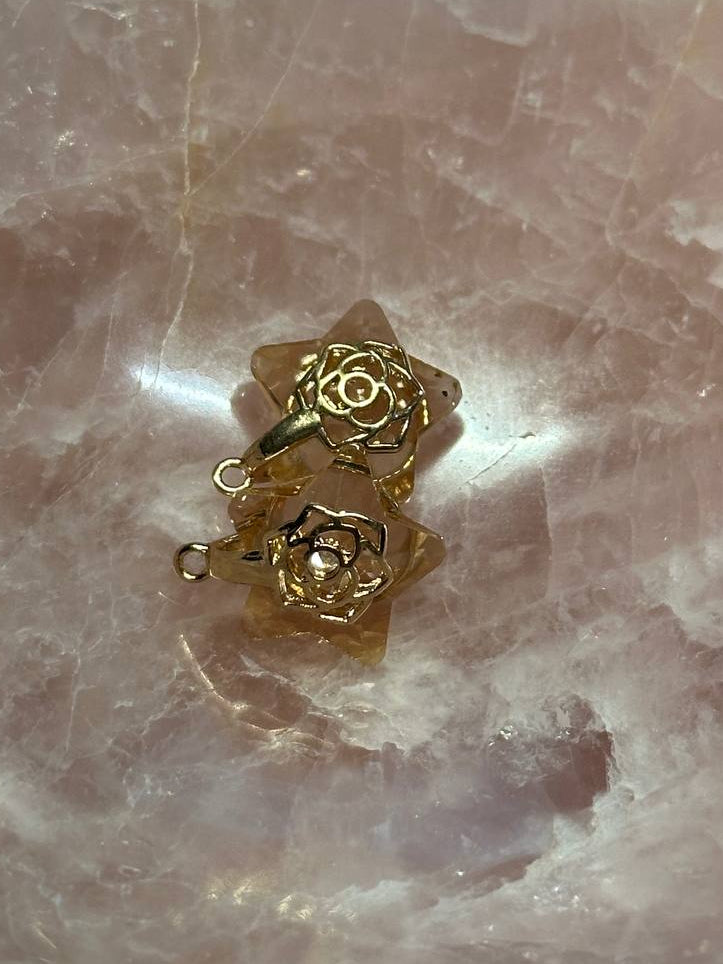 Gold flower-shaped charms on a pink stone surface