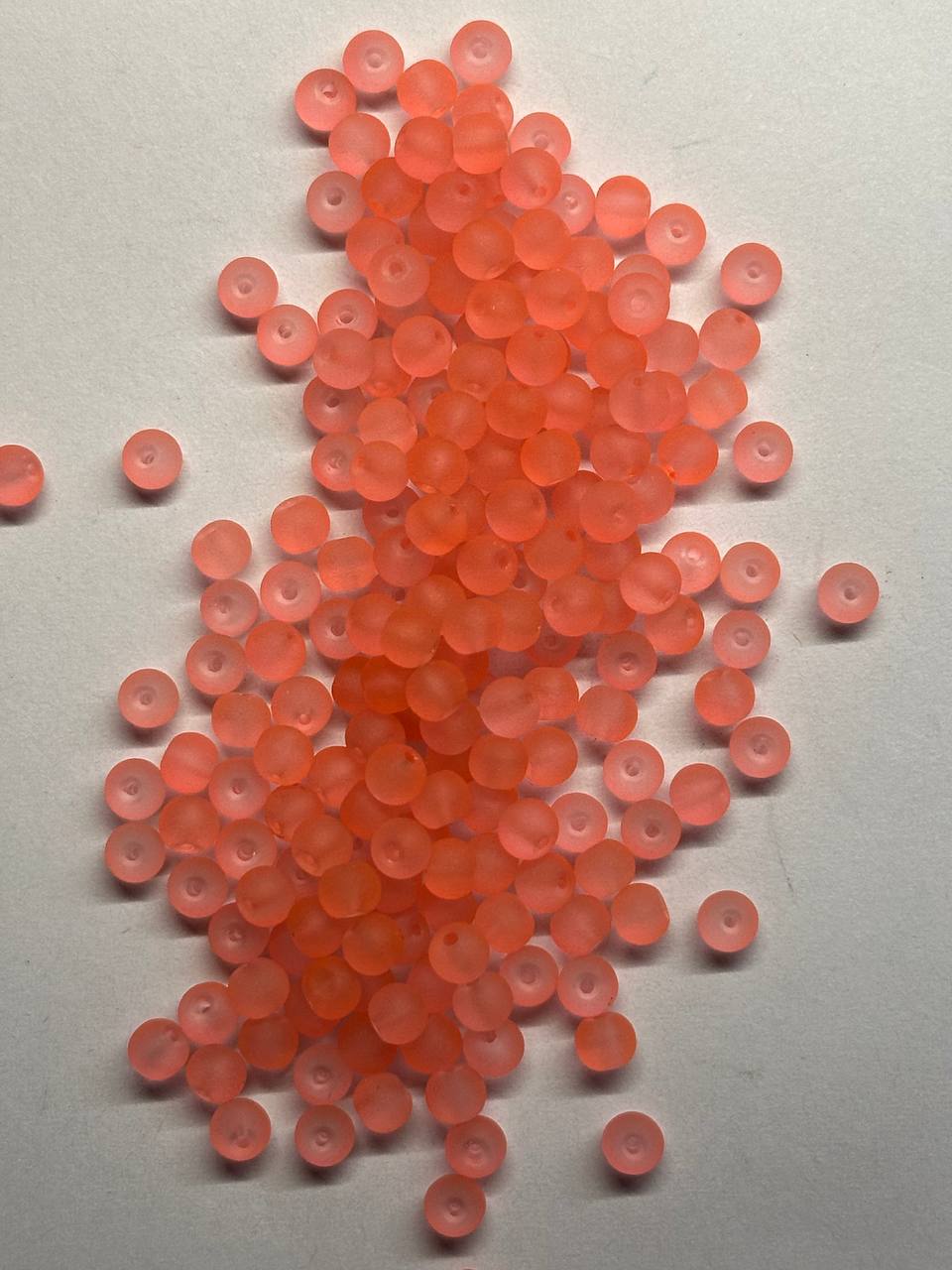 Pile of small salmon beads on a light gray background
