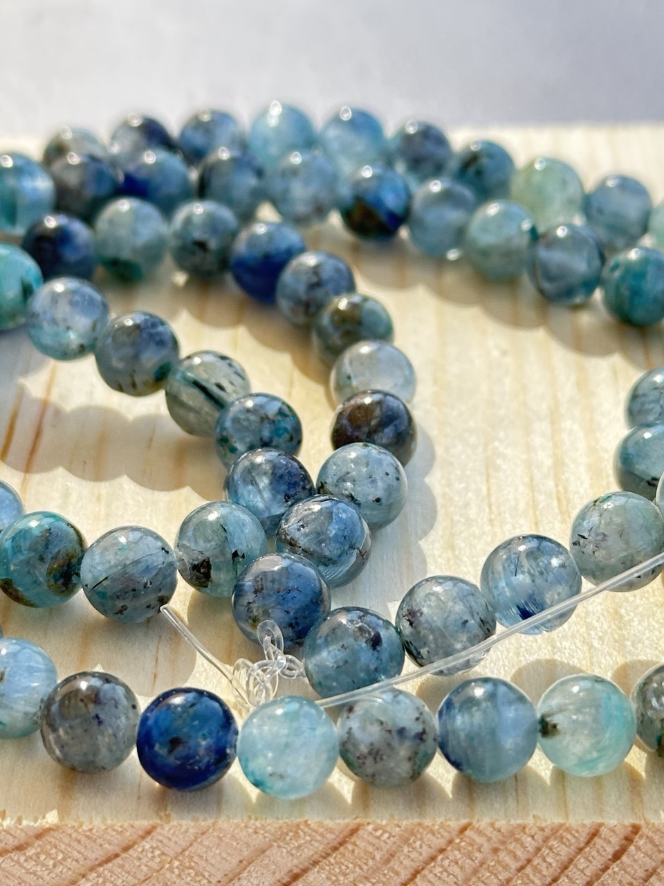 Strand of blue and green kyanite beads on a light wooden surface