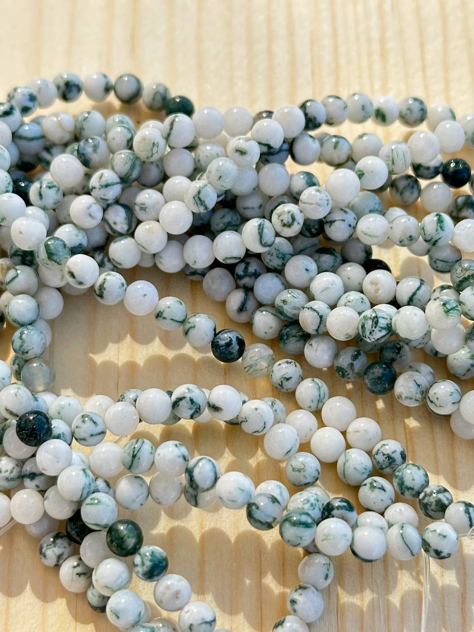 String of multicolored tree agate beads on a wooden surface