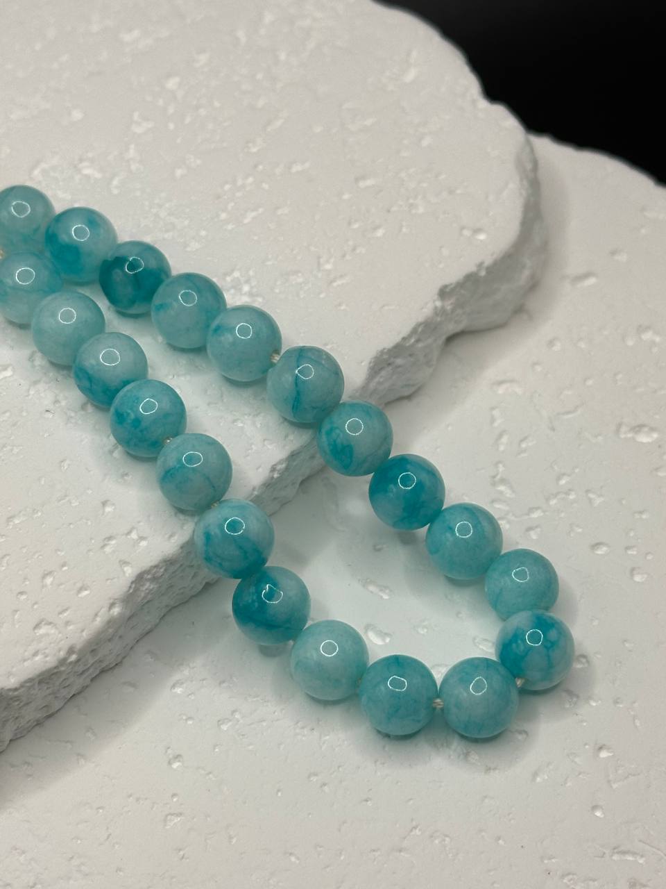 Turquoise beaded necklace on a textured white surface