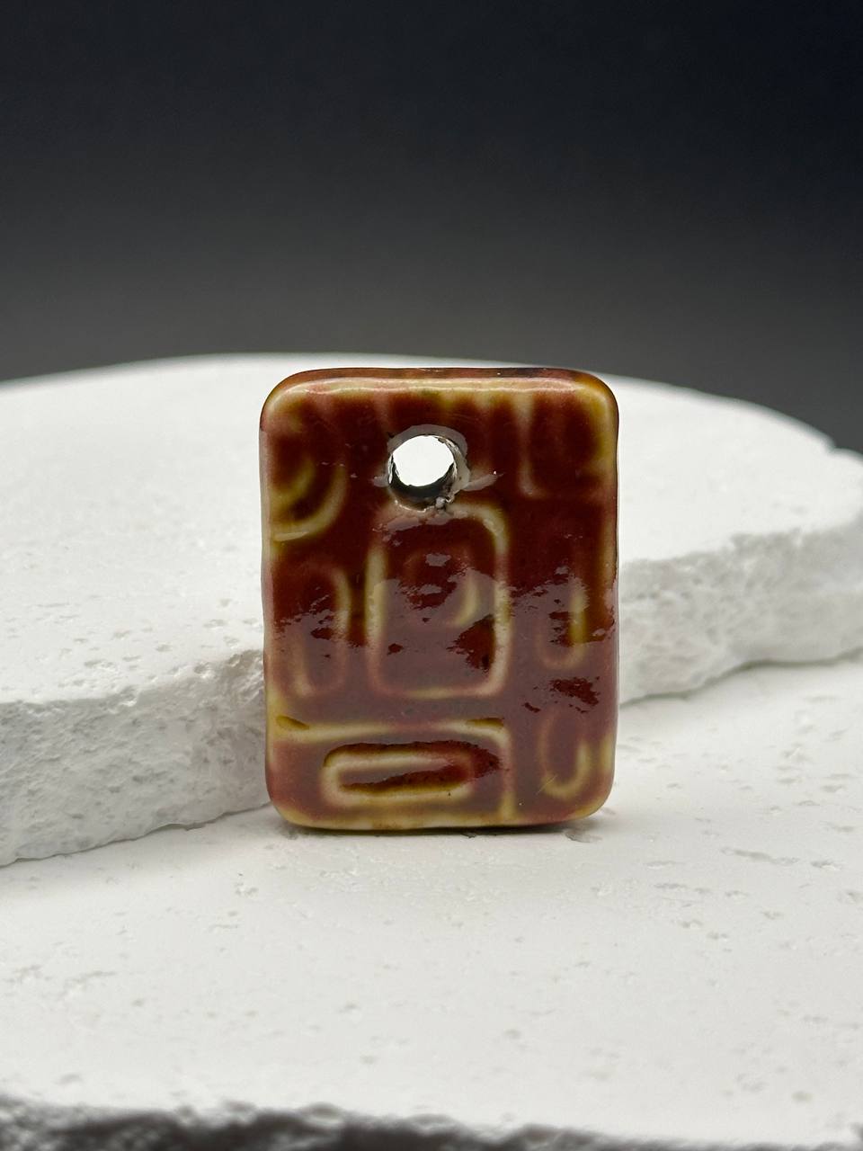 Rectangular ceramic pendant with an accent on a white surface