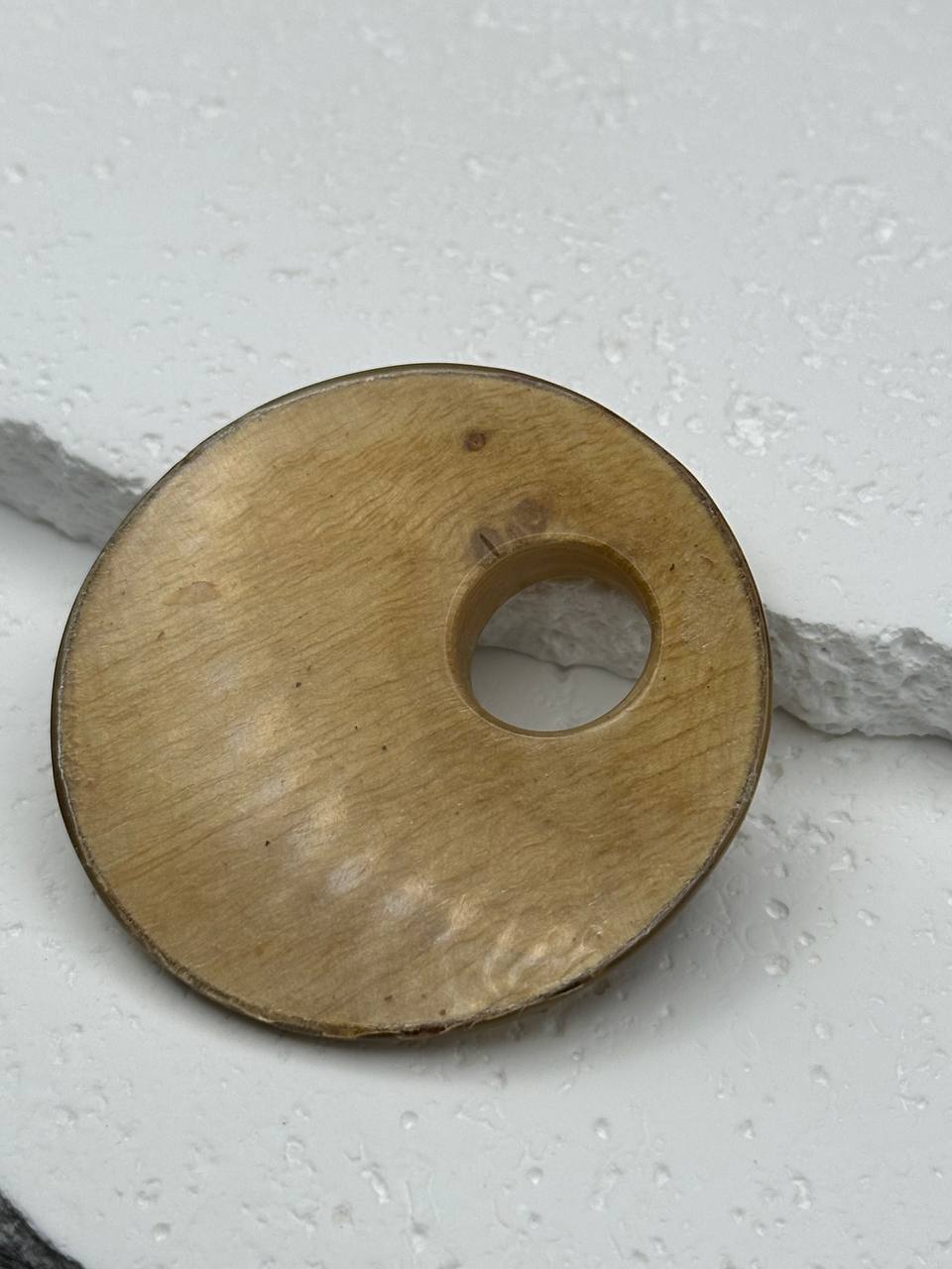 Wooden disc with a hole on a light gray background