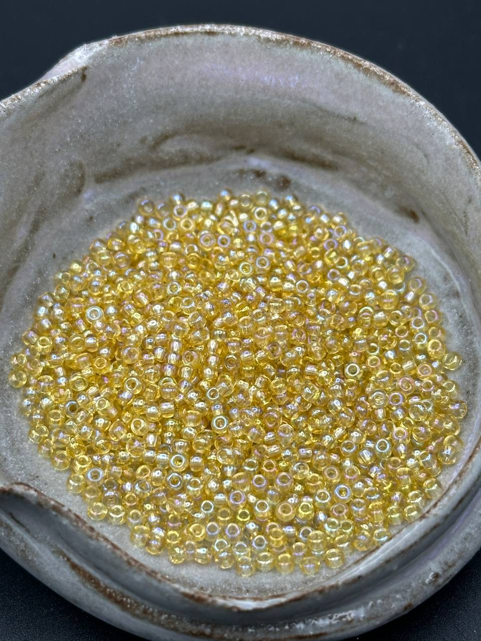 Small container filled with yellow beads on a dark background