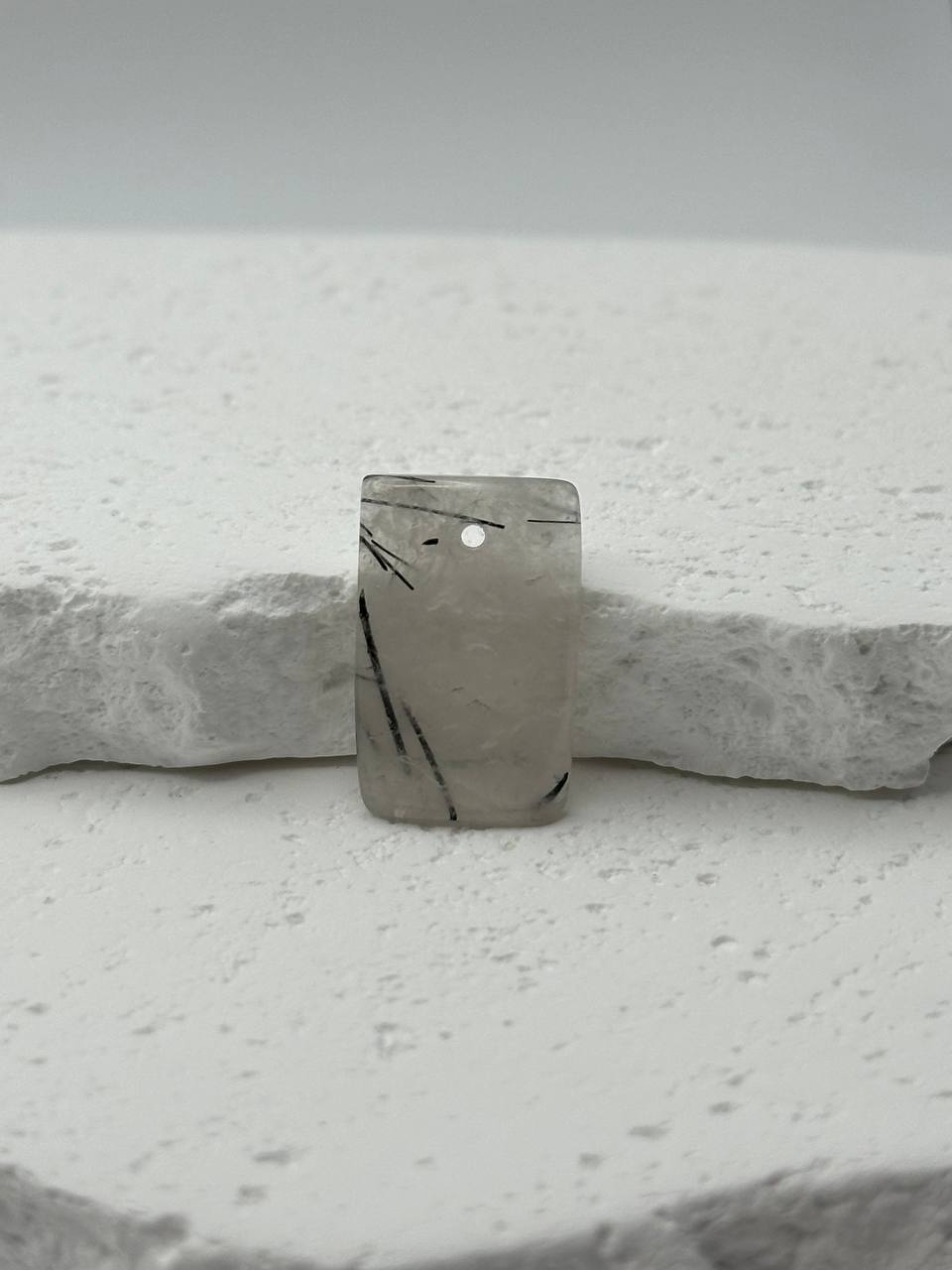 Marble-patterned stone pendant on a white stone surface