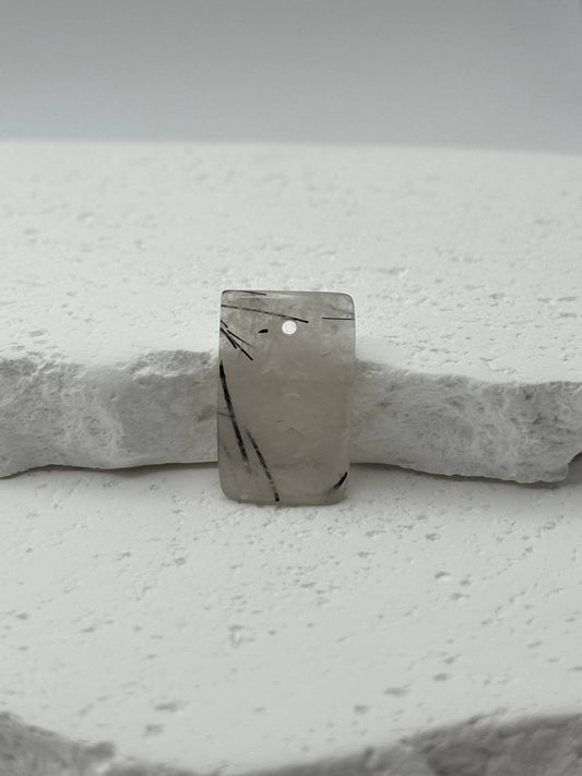 Marble-patterned stone pendant on a white stone surface