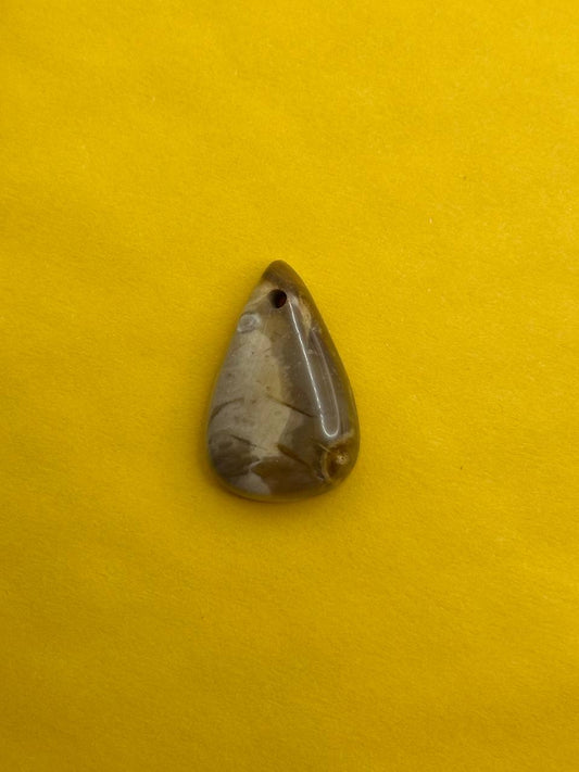 Teardrop-shaped stone pendant on a yellow background