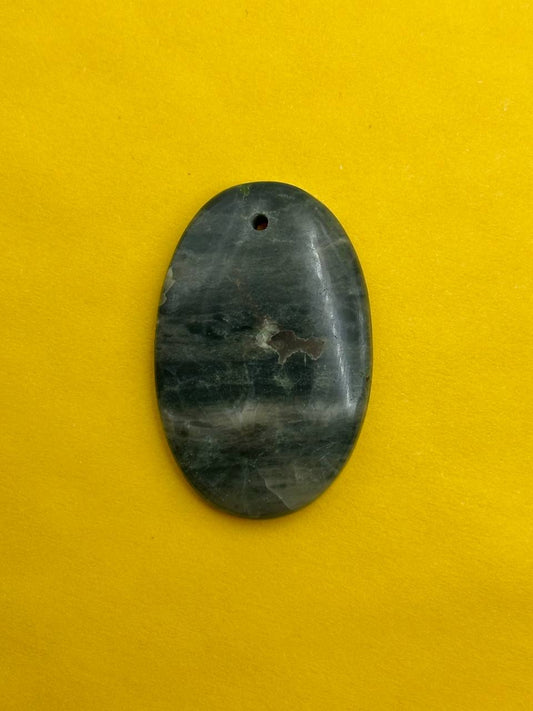 Oval-shaped stone pendant on a yellow background