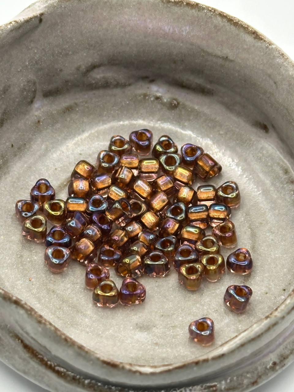 Small triangle glass beads in a metallic finish on a textured surface