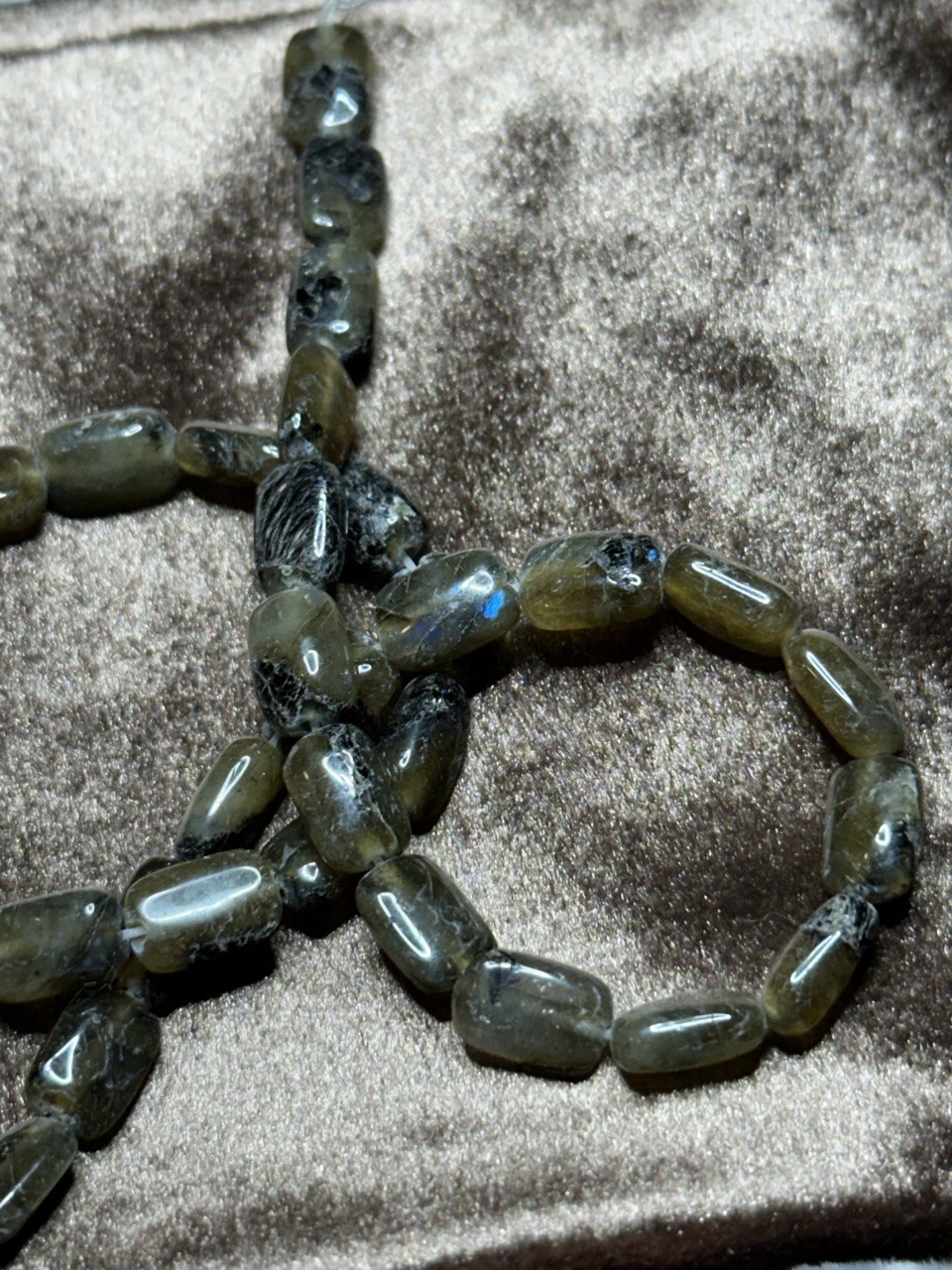 String of grey and smoky beads with blue inclusions on a textured surface