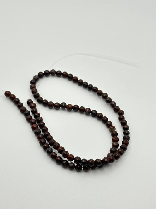 A string of dark red brecciated jasper round beads on a white surface