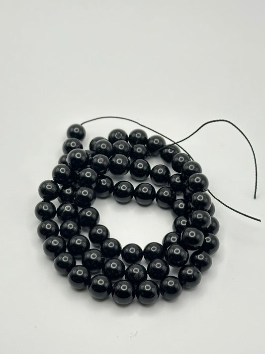 A string of black onyx round beads on a white surface