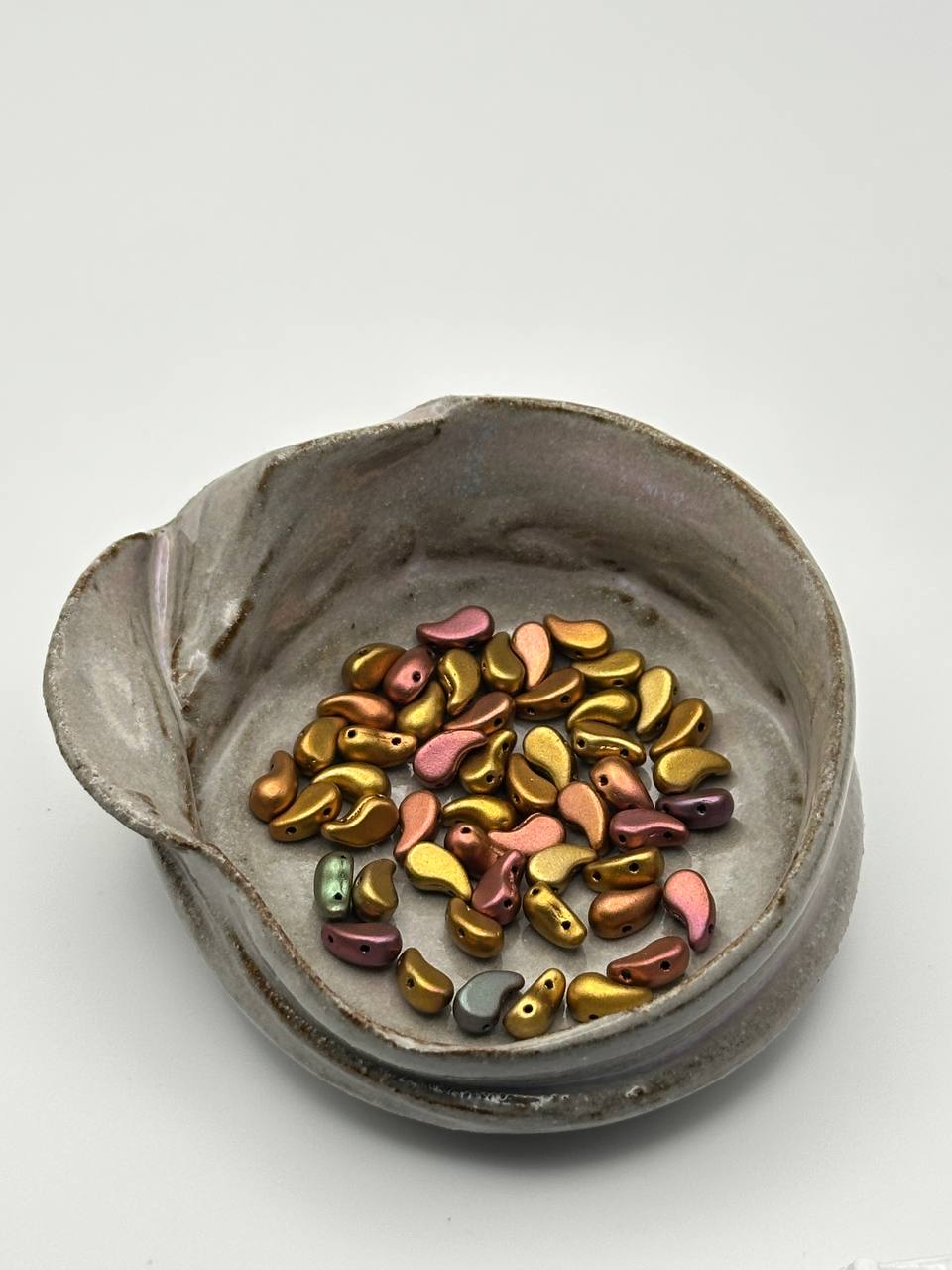 Ceramic bowl with colorful beads on a white background