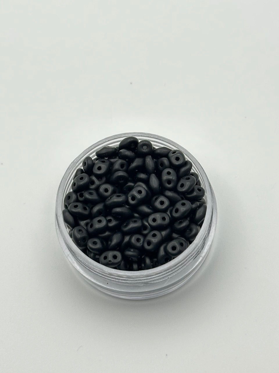 Small container filled with black beads on a white background
