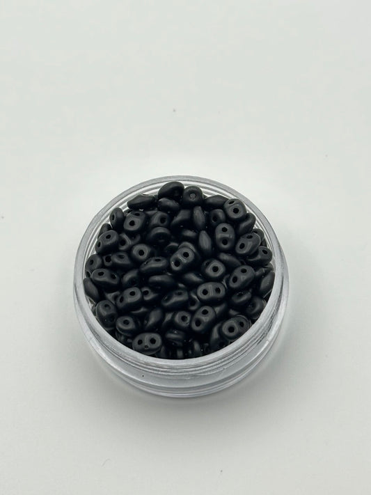 Small container filled with black beads on a white background