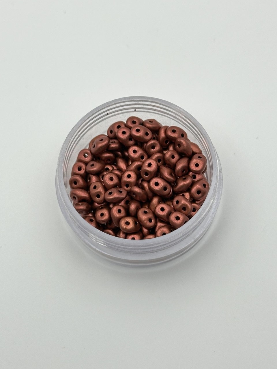 Jar of small metallic beads on a light gray background