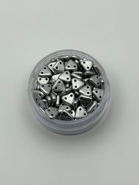 Jar of silver triangle beads on a light gray background