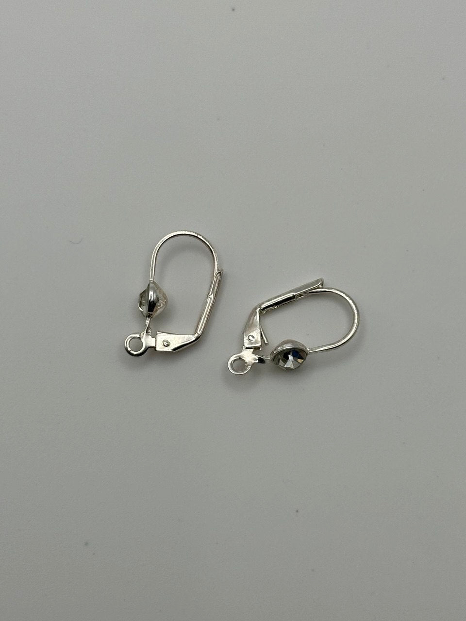 Pair of silver earrings with rhinestones on a gray background
