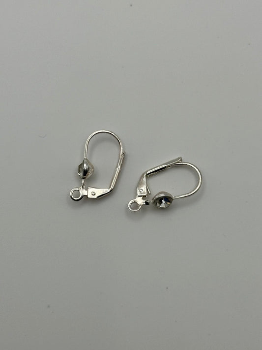 Pair of silver earrings with rhinestones on a gray background