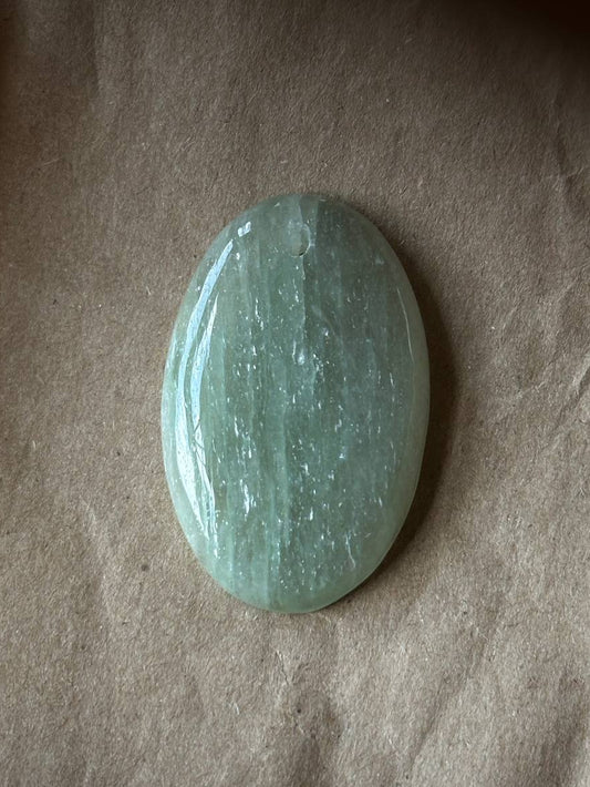 An oval aquamarine cabochon on brown paper background