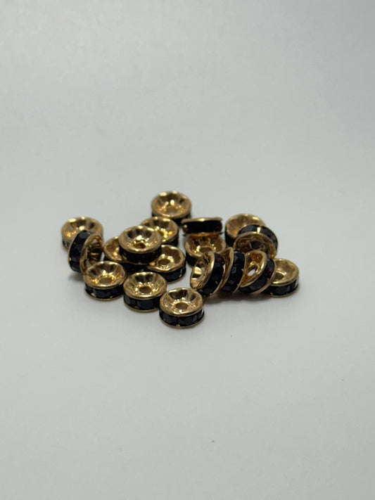 A pile of gold plated brass round spacers with garnet rhinestones