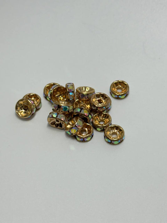 A small pile of gold plated brass round spacer beads with crystal AB rhinestones