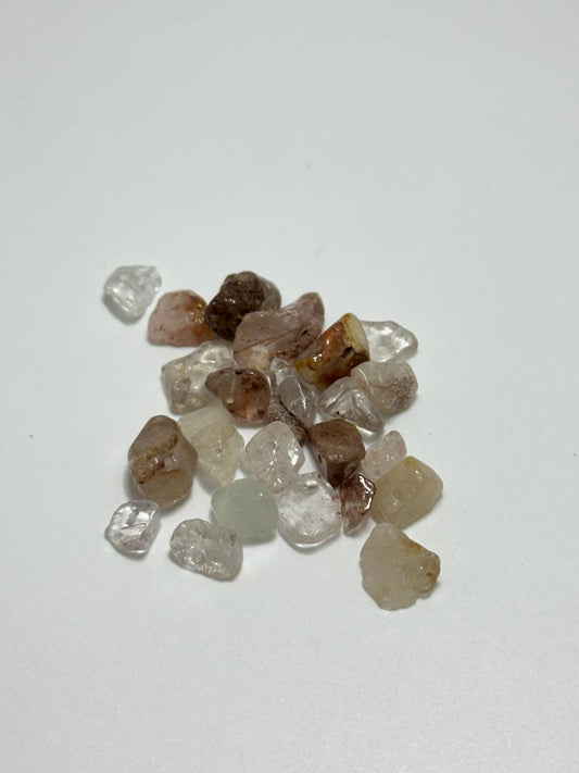 A small pile of rutilated quartz irregular chip beads on white background
