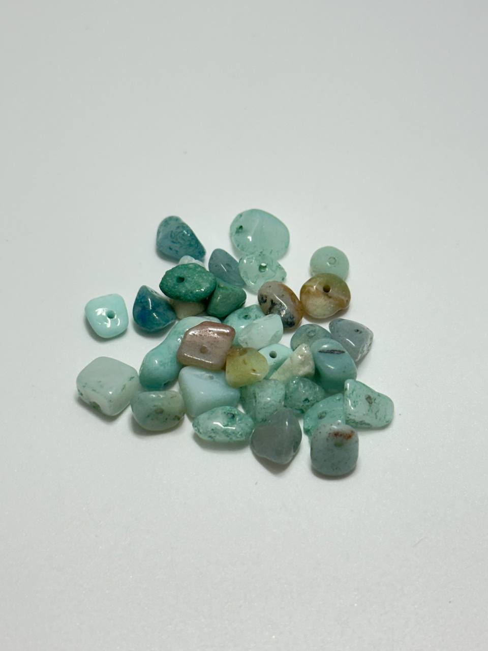 A small pile of dyed agate chip beads on white background