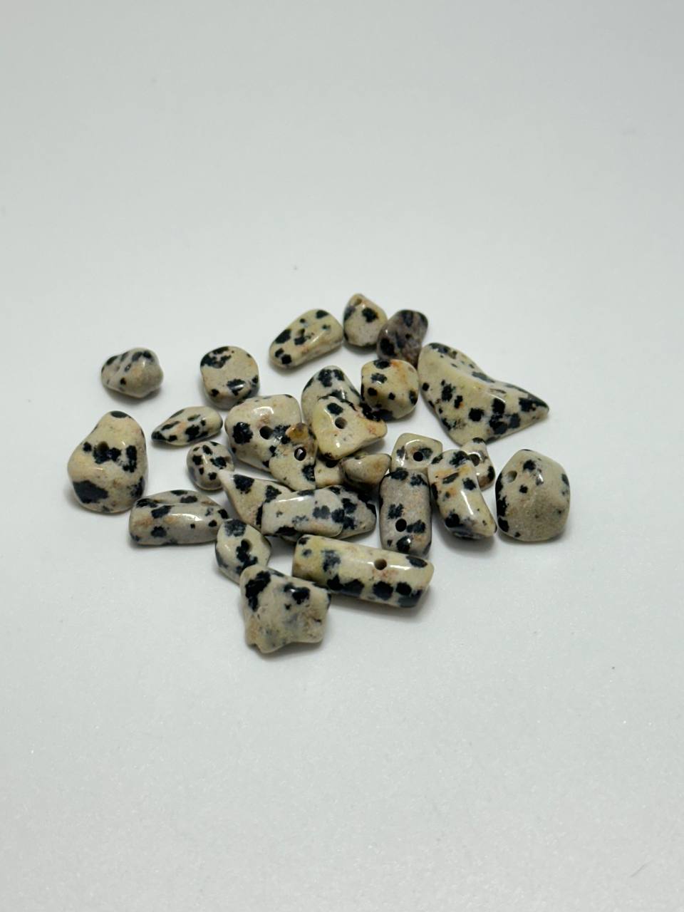 A small pile of dalmatian stone chip beads on white background