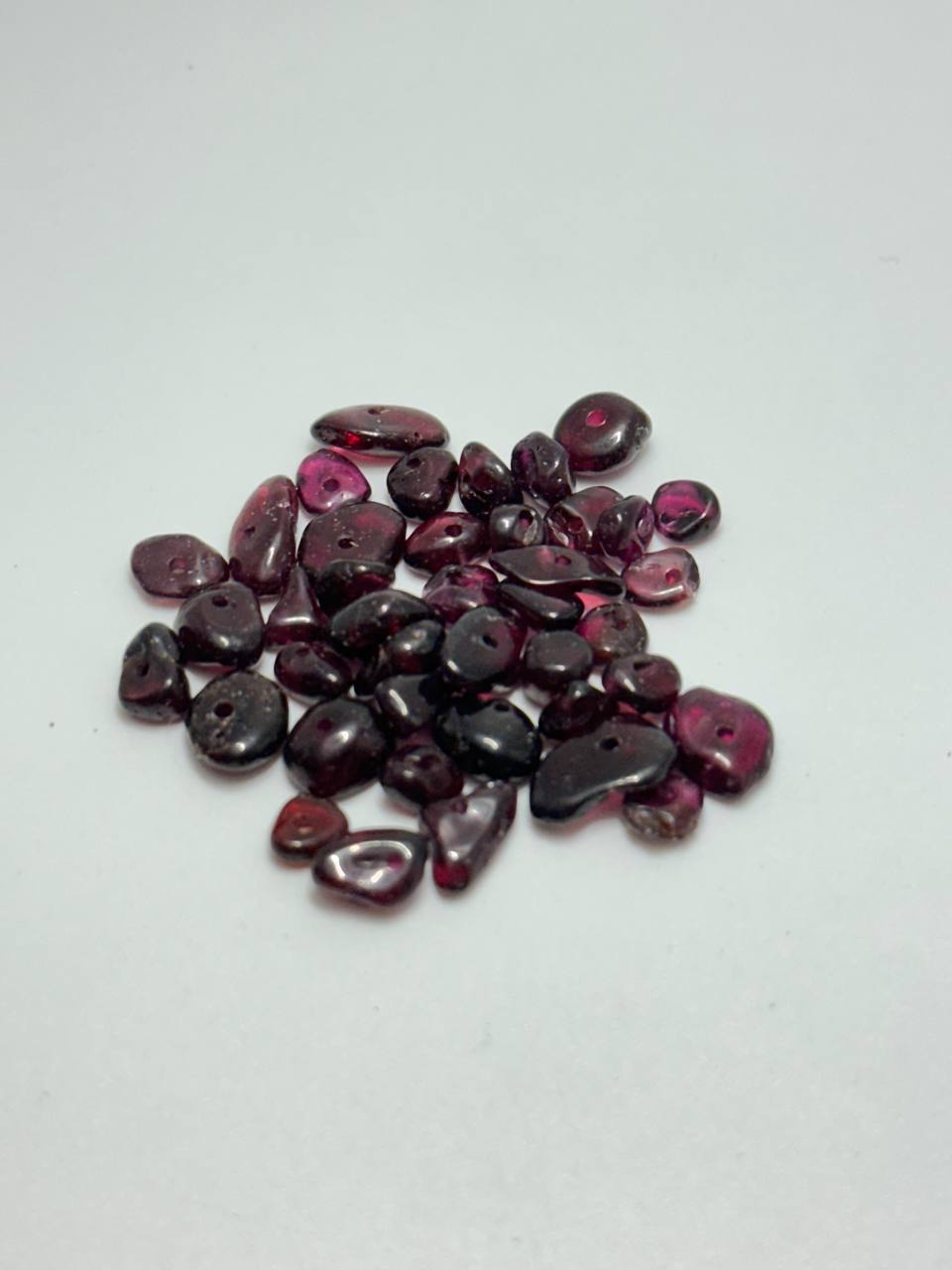 A small pile of garnet chip beads on white background