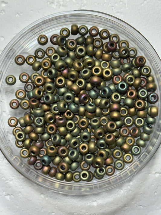 A small pile of miyuki 6/o size metallic khaki iris matte beads on white surface
