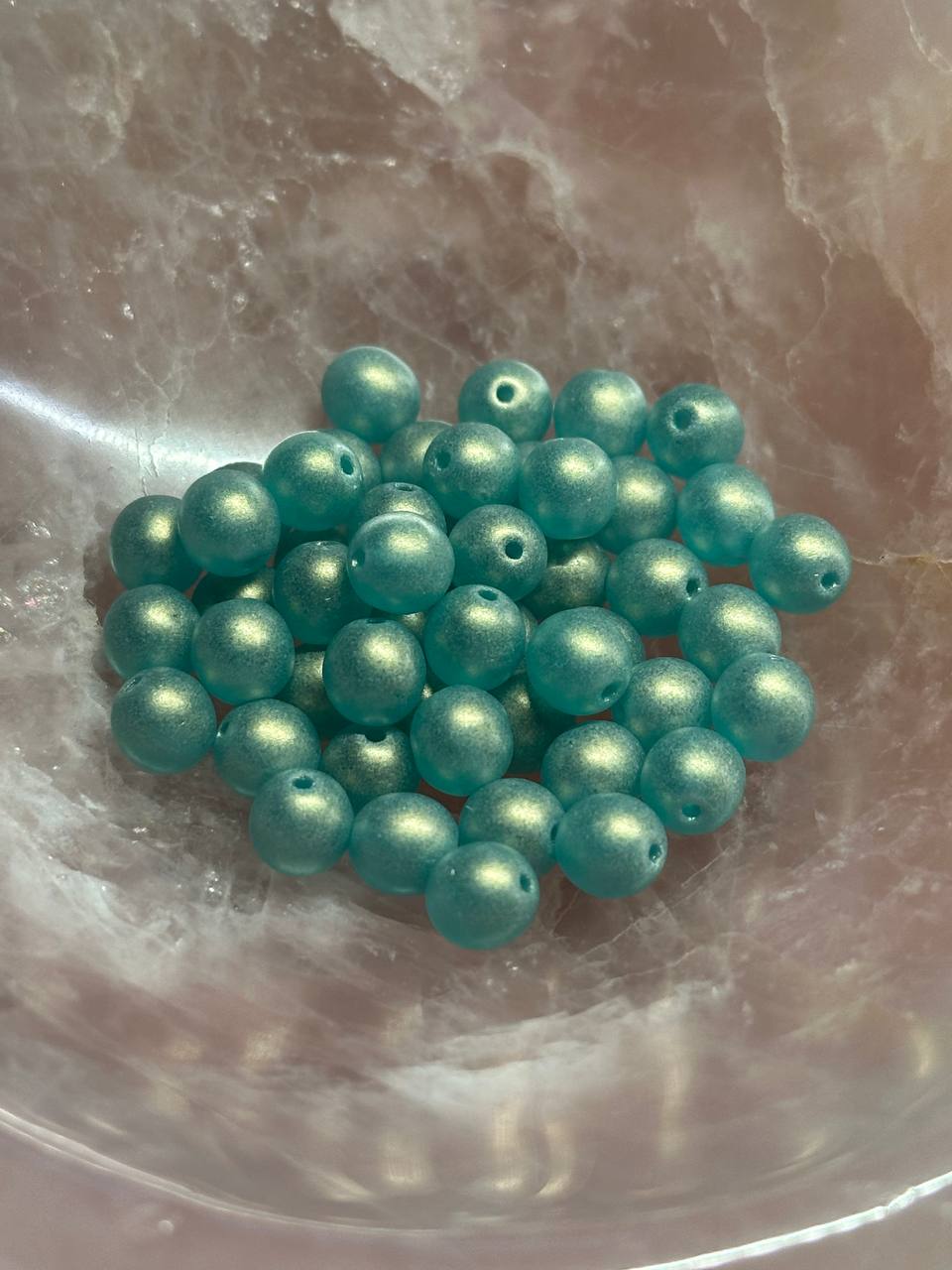 Teal beads on a marble surface