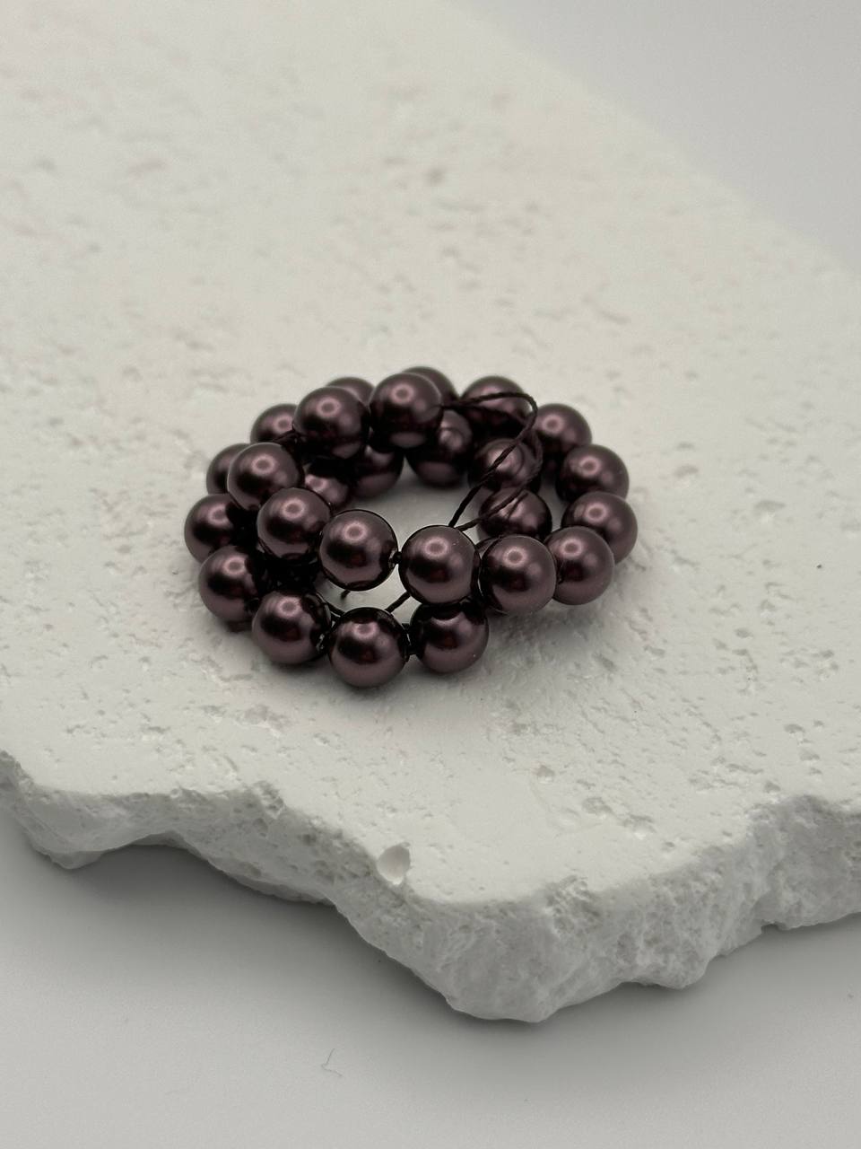 Burgundy crystal pearls on a textured white stone surface