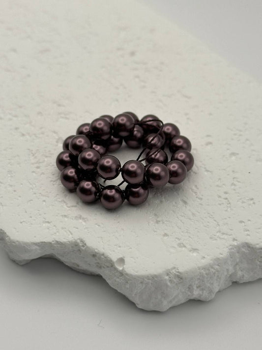 Burgundy crystal pearls on a textured white stone surface