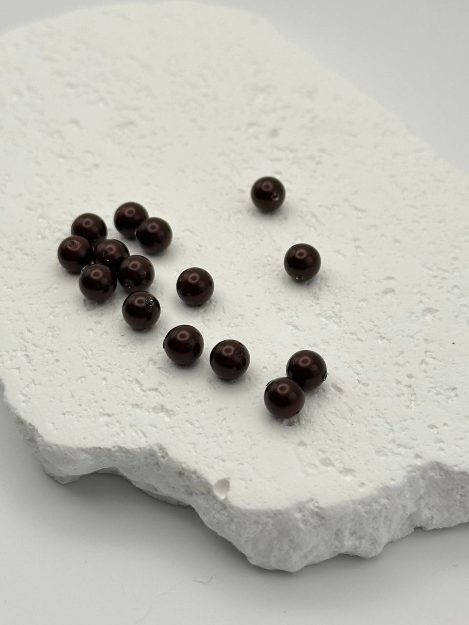Maroon crystal pearls on white surface