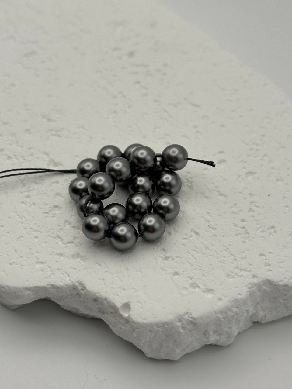 Grey crystal pearls on a textured white surface
