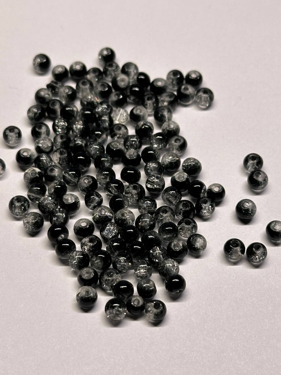 Pile of small black and gray beads on a light gray background