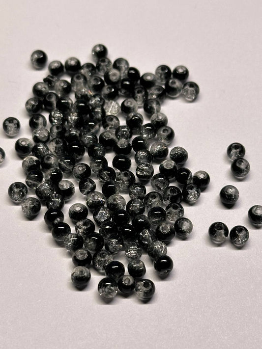 Pile of small black and gray beads on a light gray background