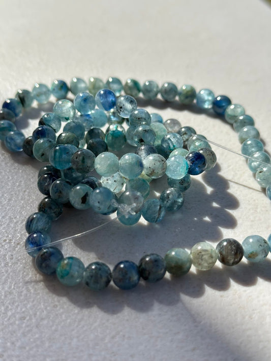 String of blue and green kyanite beads on a white surface