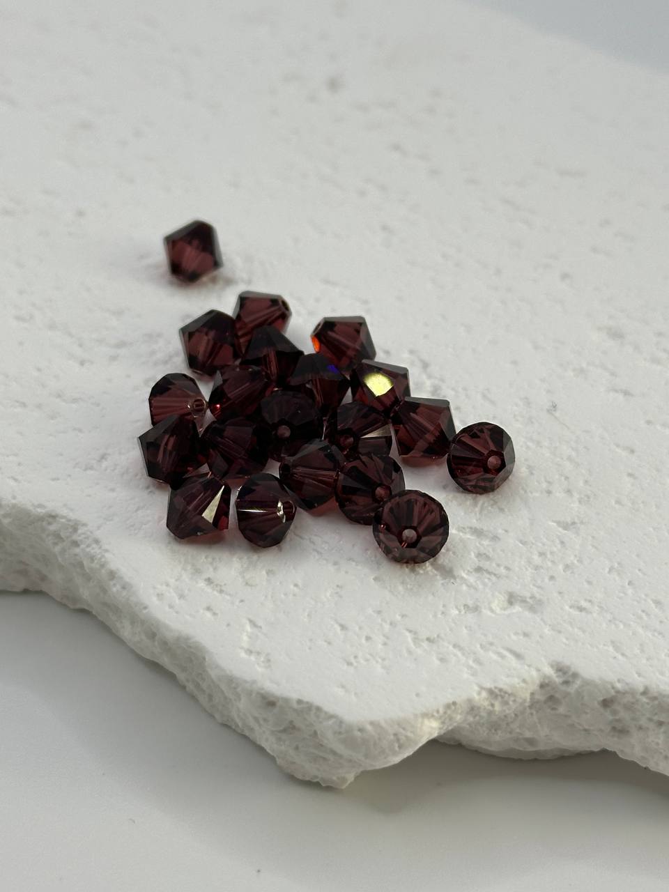 Burgundy bicone beads on white surface